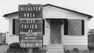 Boarded up house with sign saying 'disaster area'