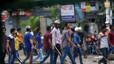 Men in helmets carrying sticks and rods