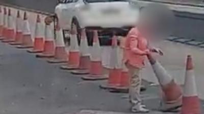 She is seen getting out of her car in traffic before trying to cut through to the other carriageway.