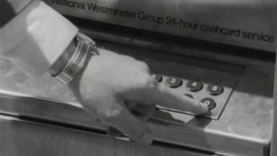 man using one of the first cash machines in 1967