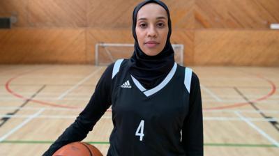 A woman in a hijab holding a basketball