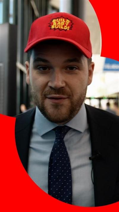 BBC Correspondent Henry Zeffman wearing a suit and tie - and a red baseball cap with a slogan on the front.