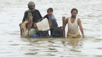 A family wade through flood waters in Pakistan