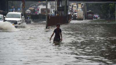 A man walks through a flooded street in Mumbai