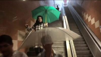 People with umbrellas in underground station