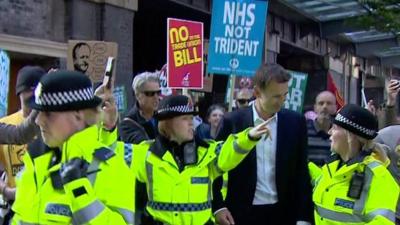 Jeremy Hunt with police officers and protesters
