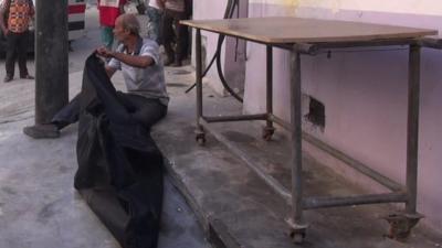 Man sits alongside the body of his son in Aleppo, Syria