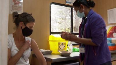 Woman about to receive vaccine from volunteer