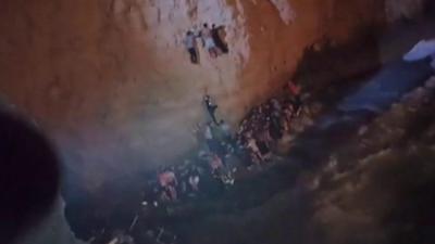 Migrants being rescued off a cliff in Greece.