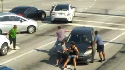 Passersby try to stop a moving car