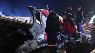 Firefighters stand near train wreckage