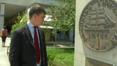 James Reynolds looking at a monument to the former Greek currency, the Drachma