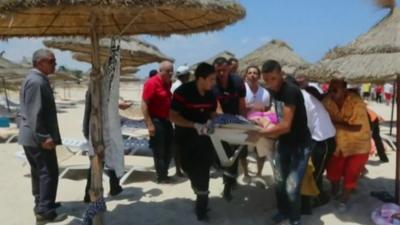 Emergency services carrying woman on stretcher off beach