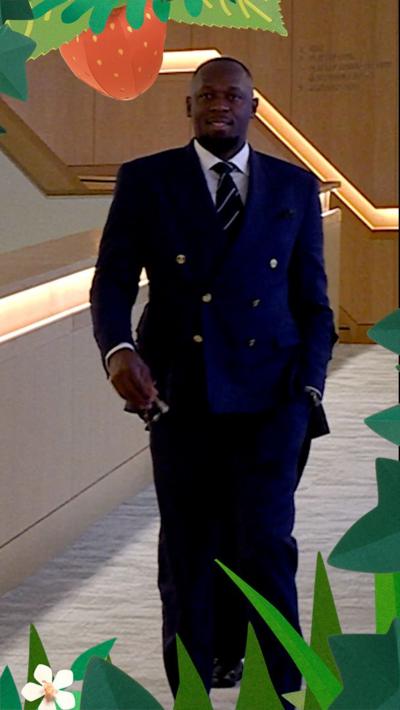 Usain Bolt wearing a Wimbledon dark green suit and stripey tie 