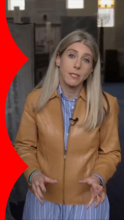BBC special correspondent Judith Moritz wearing beige jacket and standing inside of Heaton Park synagogue