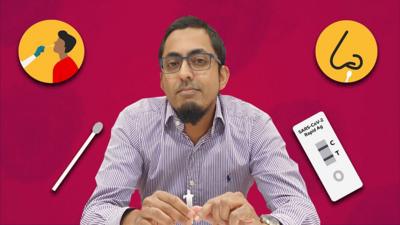 Dr Suleman Rahman surrounded by the items of a lateral flow test kit