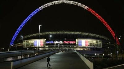 Wembley Stadium arch illuminated in the French tricolour at night