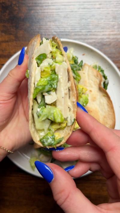 Chicken Caesar tacos on a white plate with one being lifted up so you can see the filling 