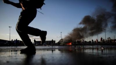 Man running past burning car