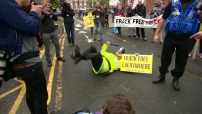 Anti fracking protestor dressed as policeman lying in road