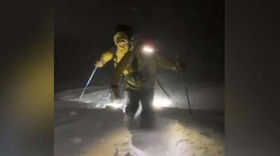 Cairngorm Mountain Rescue Team battling in the dark through deep snow with yellow jackets on and head torches.