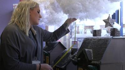 Charlotte decorating a window display.