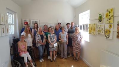 A group of people, some with brain injuries, standing in a room of paintings