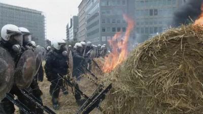 Police guarding a hay bale set on fire in farmer protests