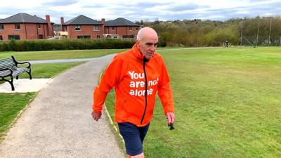 Fleming Keery is about to turn 70 and walks wearing a coat signalling a suicide prevention helpline.