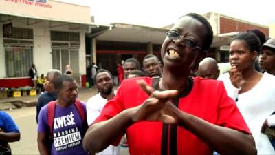 Harare resident in red jacket speaks with small group behind her