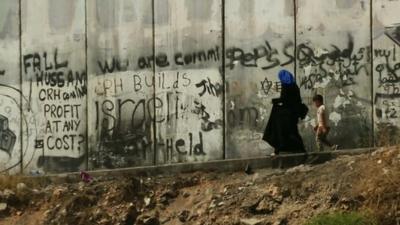 A mother and child walking beside the wall
