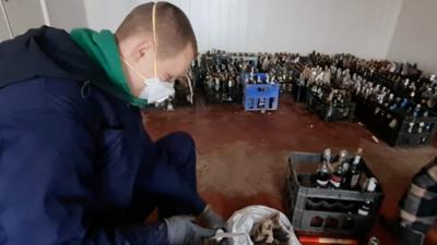 A man makes Molotov cocktails surrounded by crates of the home-made bombs