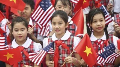 Vietnamese students hold US and Vietnamese flags at a welcoming ceremony for US President Barack Obama