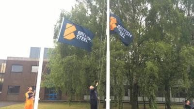 Two men raising two British Steel flags