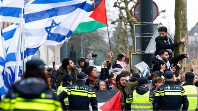 Israeli flags and Palestinian flags near police