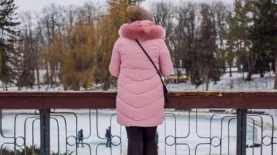 Ana, a surrogate, looks out onto an ice-rink