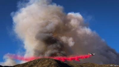 A plane drops bright red fire retardant on the Blue Cut wildfire in Lutle Creek, California