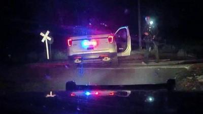 A police car with its lights on and one door open, at night