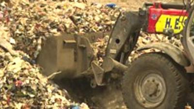 Digger shovelling waste plastic