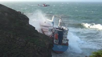 A crew member is winched to safety from a cargo ship off the coast of Sardinia