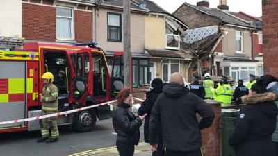 Street scene showing collapsed house and fire engine