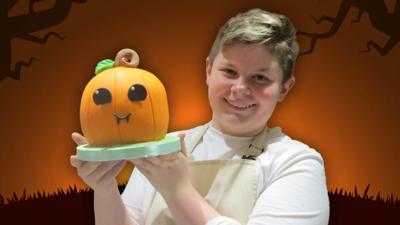Junior Bake Off winner Fin holding his pumpkin cake.