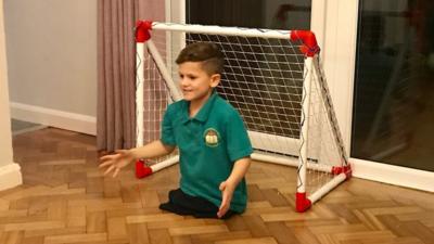 Romeo playing football in his living room