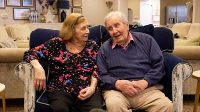 Josephine and Aubrey Langley sitting close together in double chair a lounge