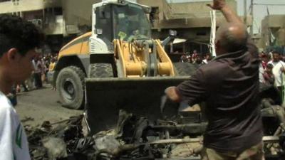 A bulldozer clears the wreckage following a car bomb attack in Sadr City