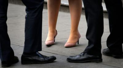 The legs of two men and a women in business attire