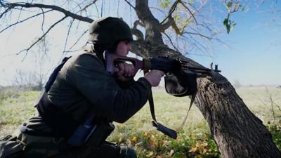 Soldier holding a gun behind a tree