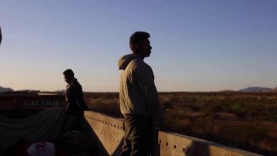 Migrant looks into the distance while on top of a train