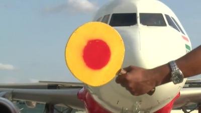 An airport worker signalling to an Indian plane