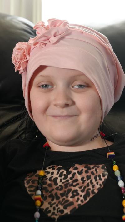 A girl in a pink headscarf smiling 